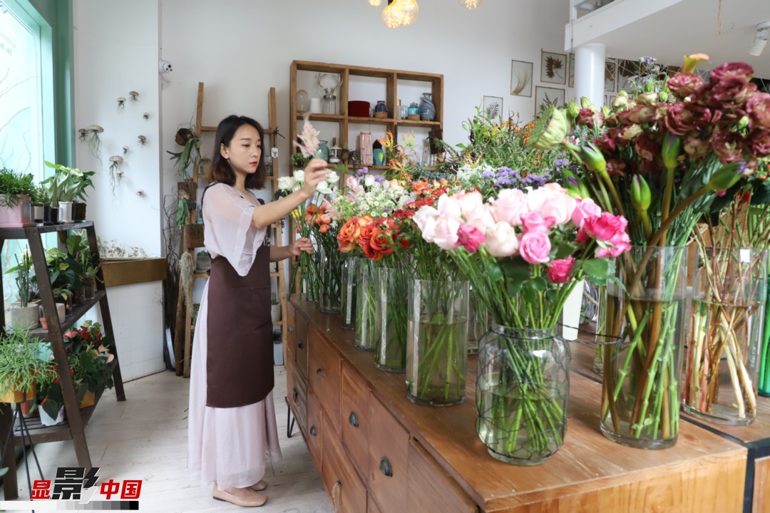 王黎媛是一名河南姑娘，在昆明念完大學(xué)后，就再也舍不下春城的藍天陽光、青山碧水，更舍不下這里的四時繁花，于是就干脆留了下來，成了一名媒體人。2017年的時候又毅然辭去工作，創(chuàng)業(yè)開起了花店，成了都市里的一名“花房姑娘”。圖為王黎媛在自己的花店中整理鮮花。新華網(wǎng) 周亞平/攝 念新洪/文